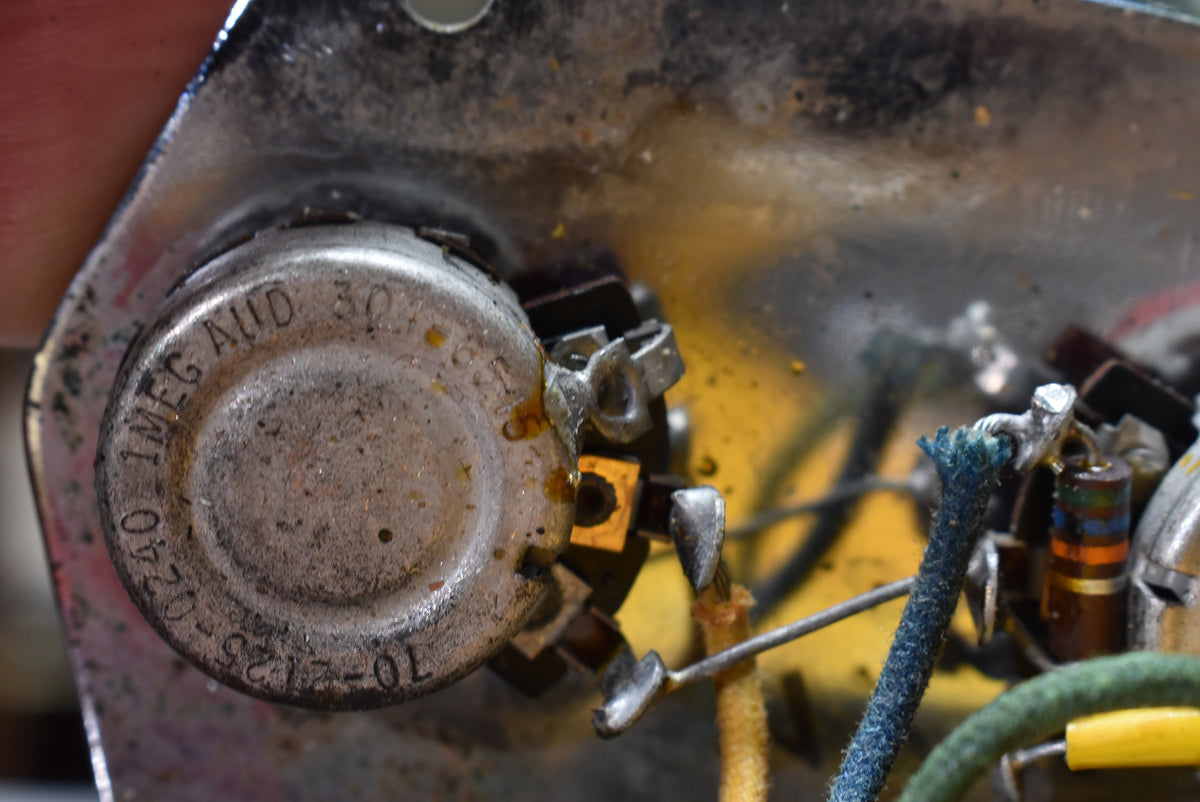 Close-up of a tarnished metal potentiometer with soldered wires, showing a "1MEG AUD 30465" stamp and other numbers.