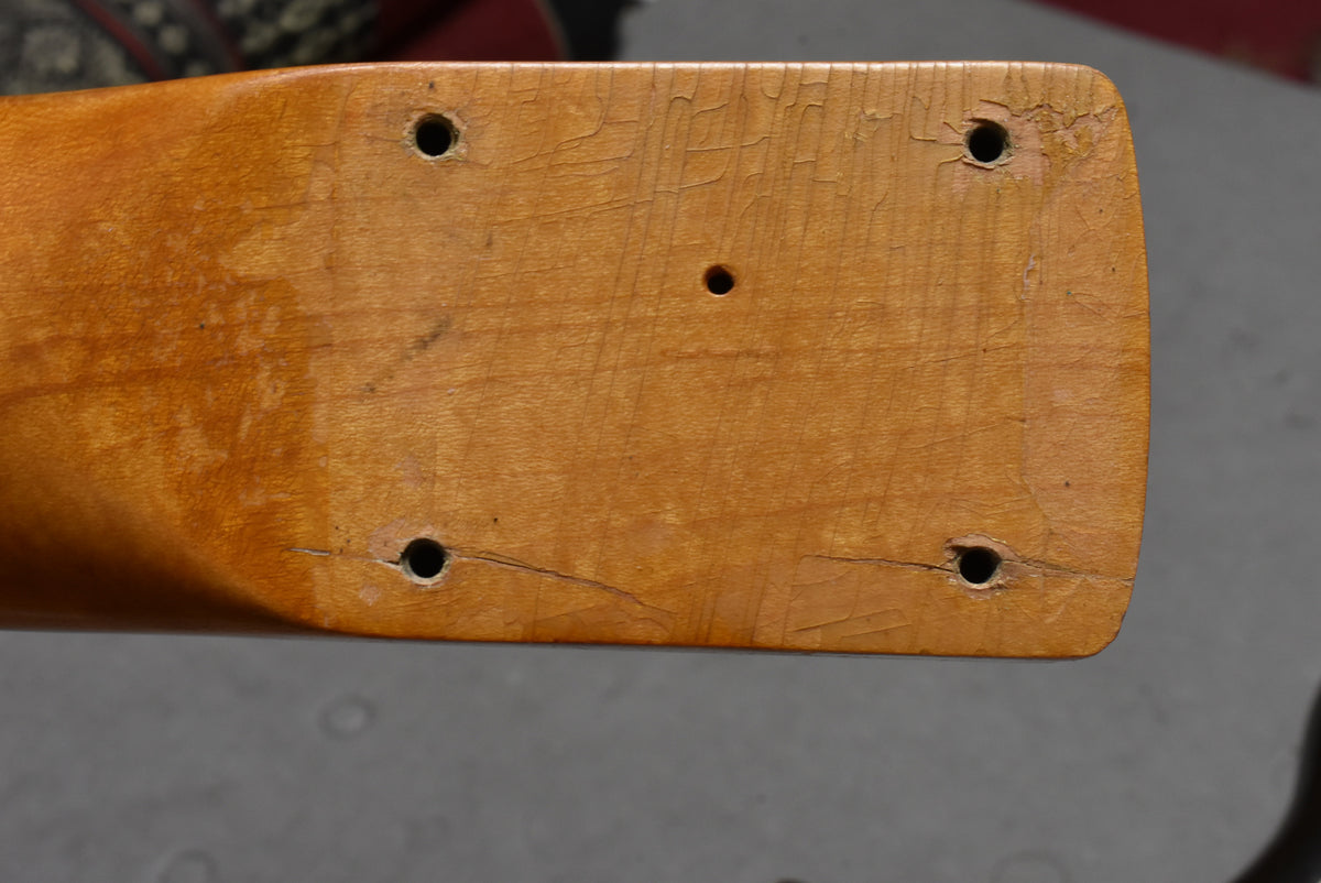 Close-up of the guitar's neck heel, showing four screw holes and a smaller central hole, with heavy finish checking and wear.