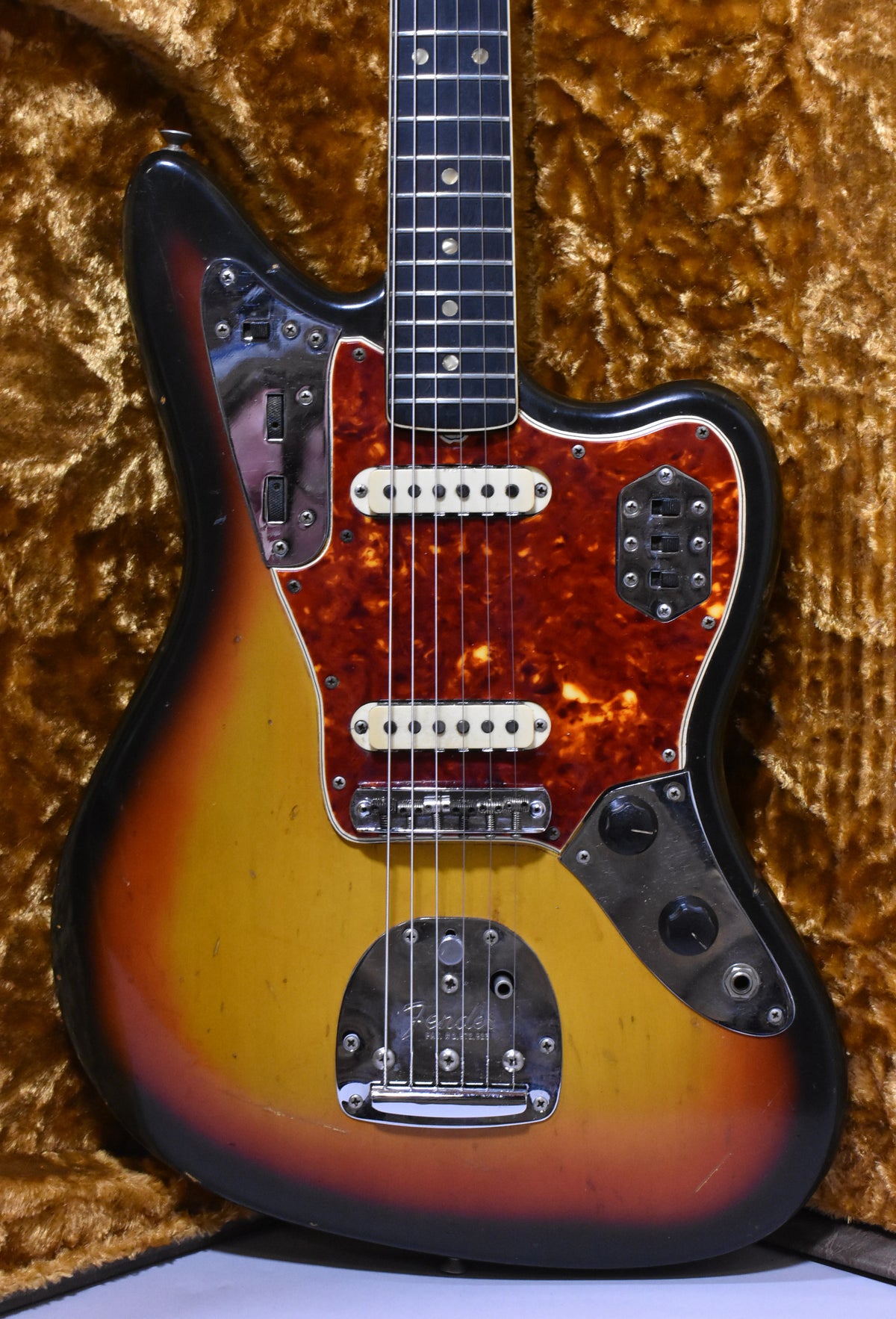 Full-body view of a sunburst guitar with a tortoiseshell pickguard, two white pickups, and chrome hardware showing wear.