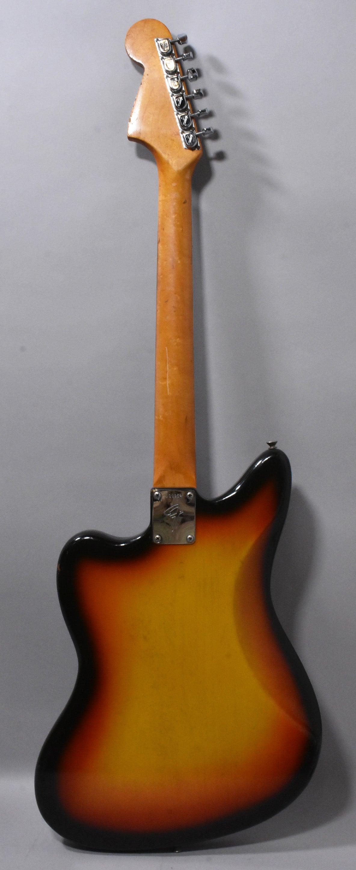 Full rear view of a sunburst electric guitar, showing the worn headstock, neck with light scratches, and body with finish checking.