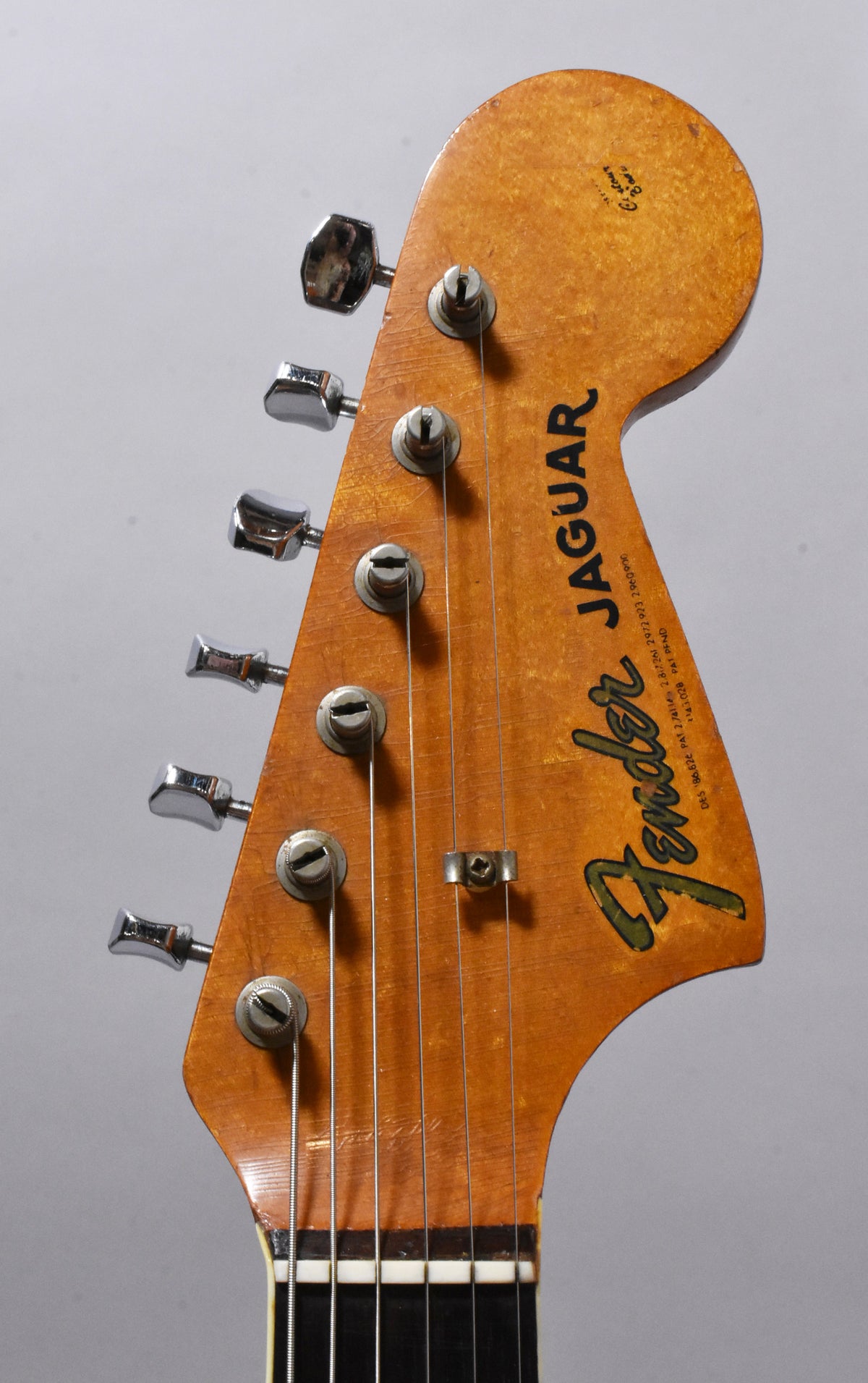 Close-up of the guitar's headstock, showing six chrome tuners, a string tree, and light finish checking on the amber-toned wood.