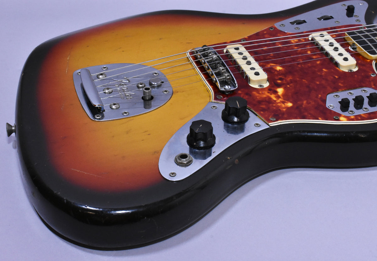 The lower body of a sunburst guitar, showing the vibrato, bridge, two cream pickups, and control plates with black knobs.