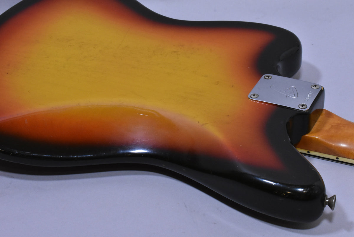 The guitar's sunburst back shows finish wear and light scratches, with a chrome neck plate and a strap button on the lower bout.