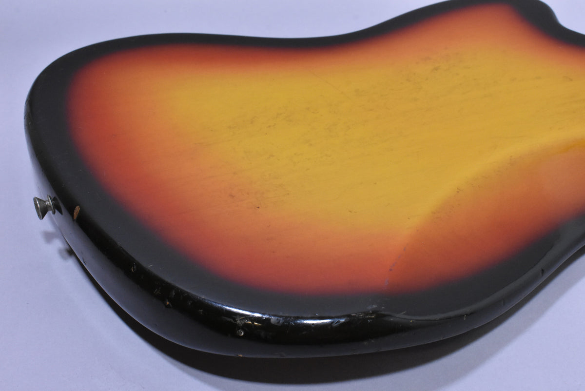 The back of a 3-tone sunburst guitar body, showing finish wear, scratches, and dings along the lower edge and strap button.