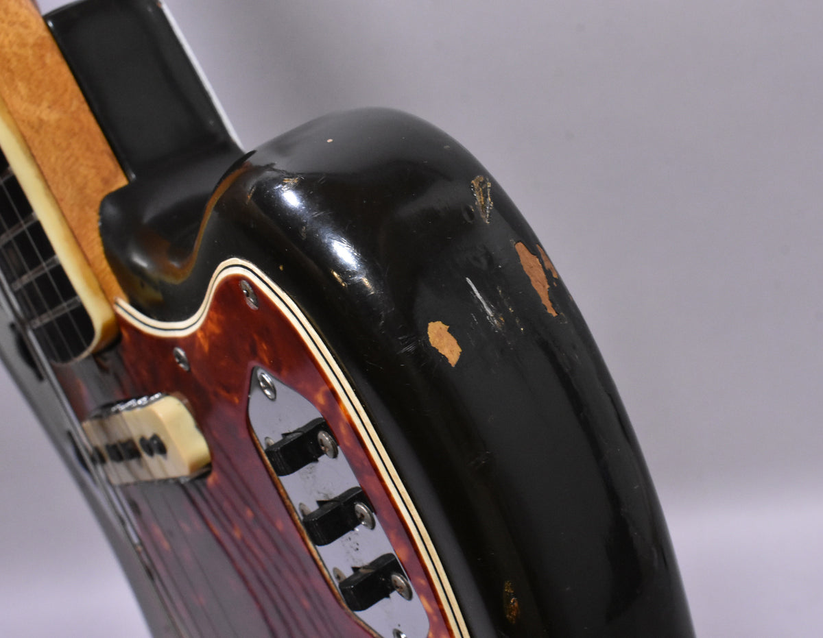 Upper bout of a sunburst guitar, showing a tortoise pickguard, three chrome slide switches, and significant finish wear.