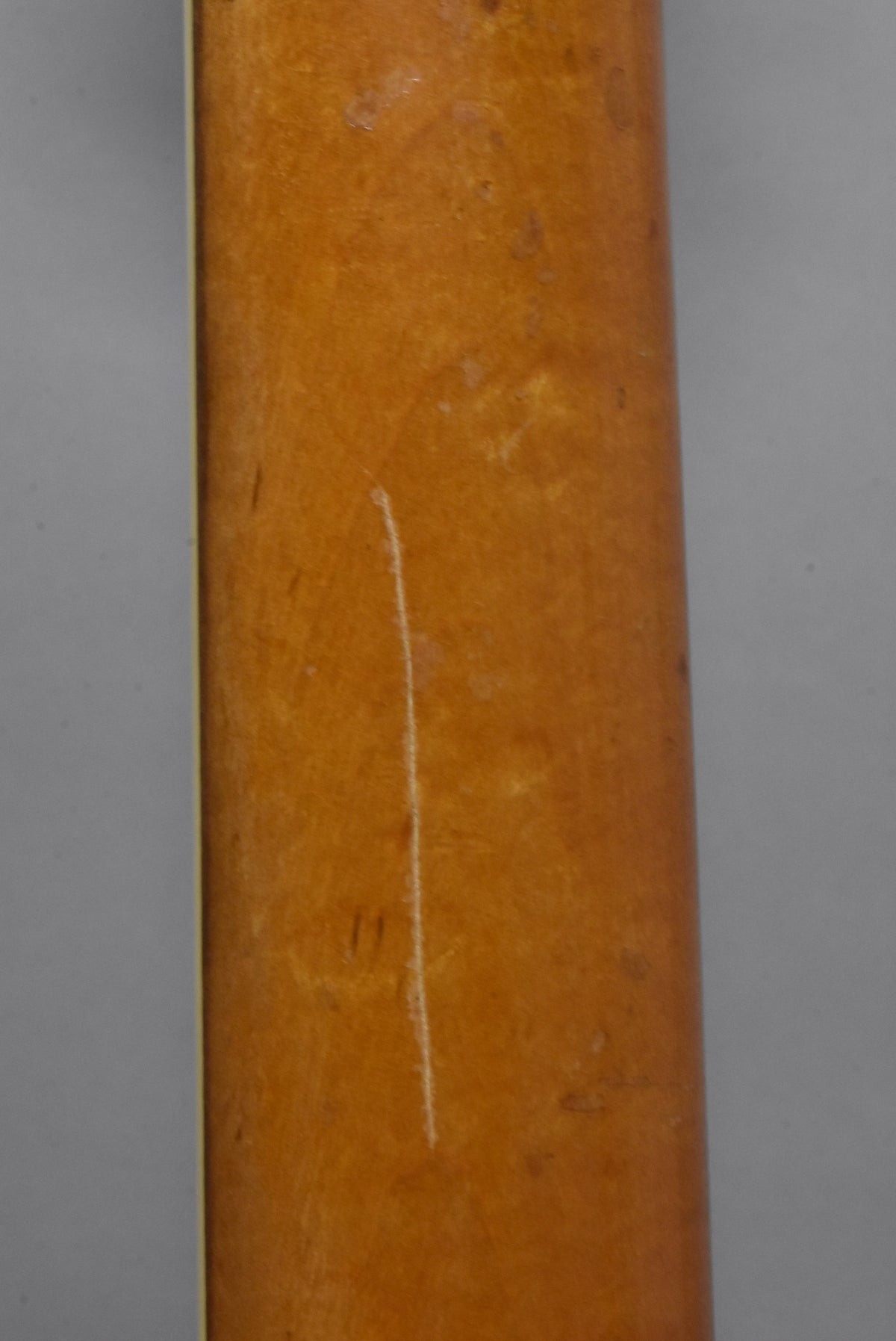 Close-up of the guitar's light brown neck, showing a prominent vertical white scratch and several smaller scuffs and indentations.