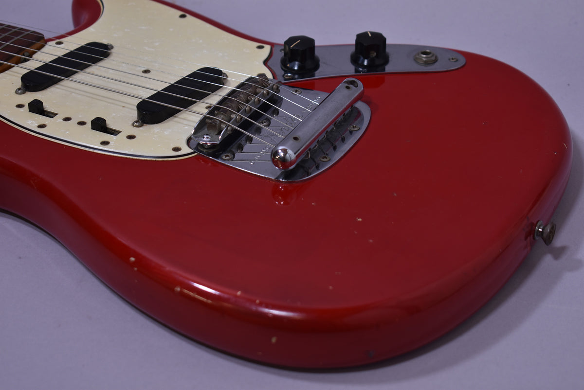 The Dakota Red guitar body, with a pearloid pickguard, shows two black single-coil pickups, a chrome bridge, and two black control knobs.