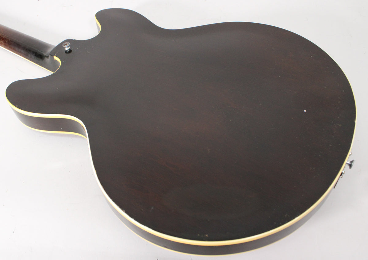 The guitar's dark sunburst back, showing some wear and light scratches, with cream binding, angled from the lower bout to the neck heel.