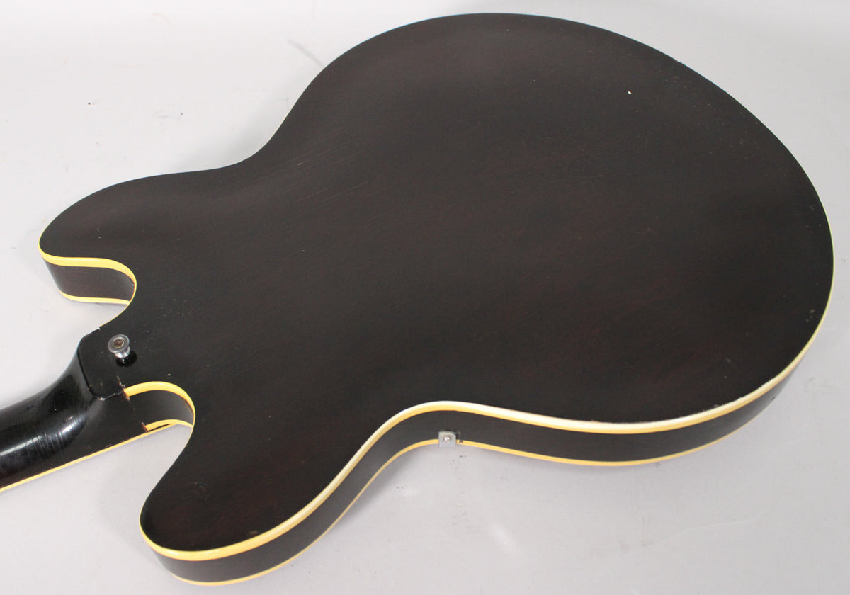 The dark brown guitar back, with cream binding, shows light wear and a strap button near the neck joint.