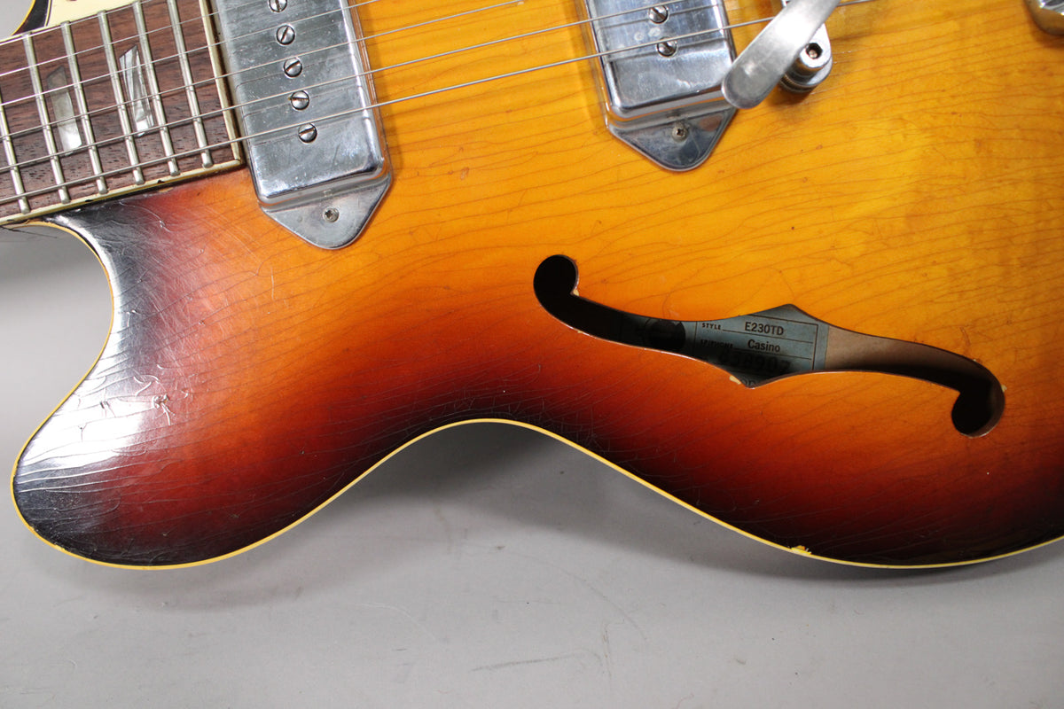 Close-up of the sunburst guitar body, showing heavy finish checking and wear on the lower bout, with a chrome pickup and f-hole visible.