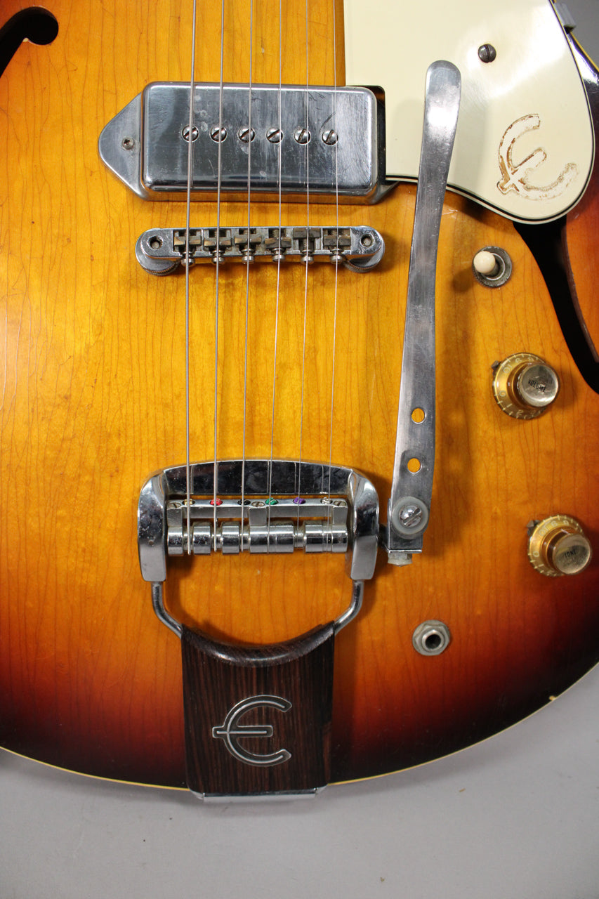 Close-up of the sunburst body, showing the bridge pickup, vibrato tailpiece, and control knobs with visible finish checking and wear.