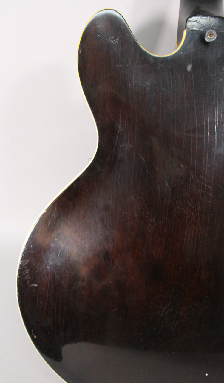 The guitar's dark sunburst back, showing heavy finish checking and scratches, with a white binding along the body's edge.