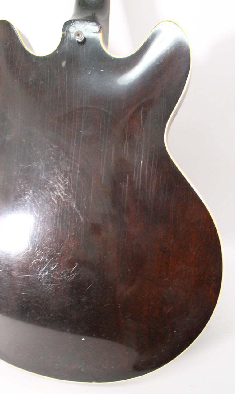 The guitar's dark sunburst back, with cream binding, shows many fine scratches and scuffs, especially near the neck heel.