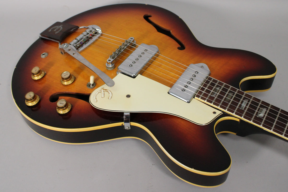 Sunburst archtop guitar, angled from the lower bout, showing the vibrato, four gold knobs, two P90 pickups, and f-holes.