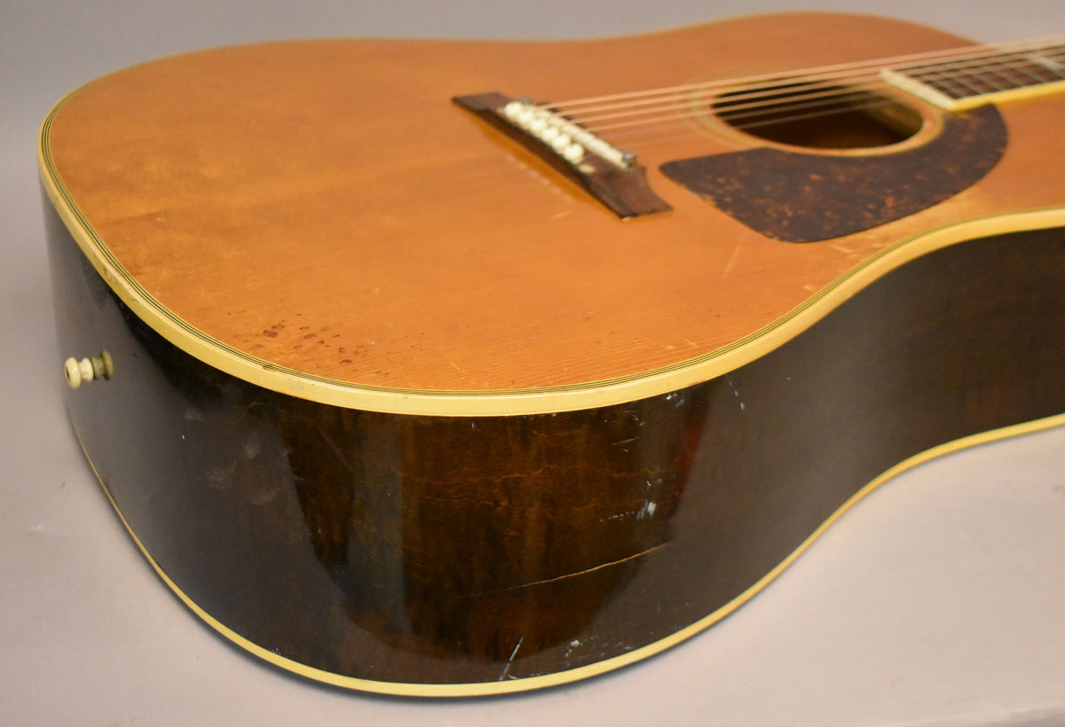 Close-up of the guitar's lower bout, showing the natural finish top with pickguard wear and dark sides with visible checking and scratches.