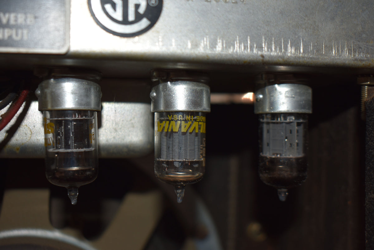 Close-up of three vacuum tubes with silver bases, showing internal components and yellow lettering on the middle tube.