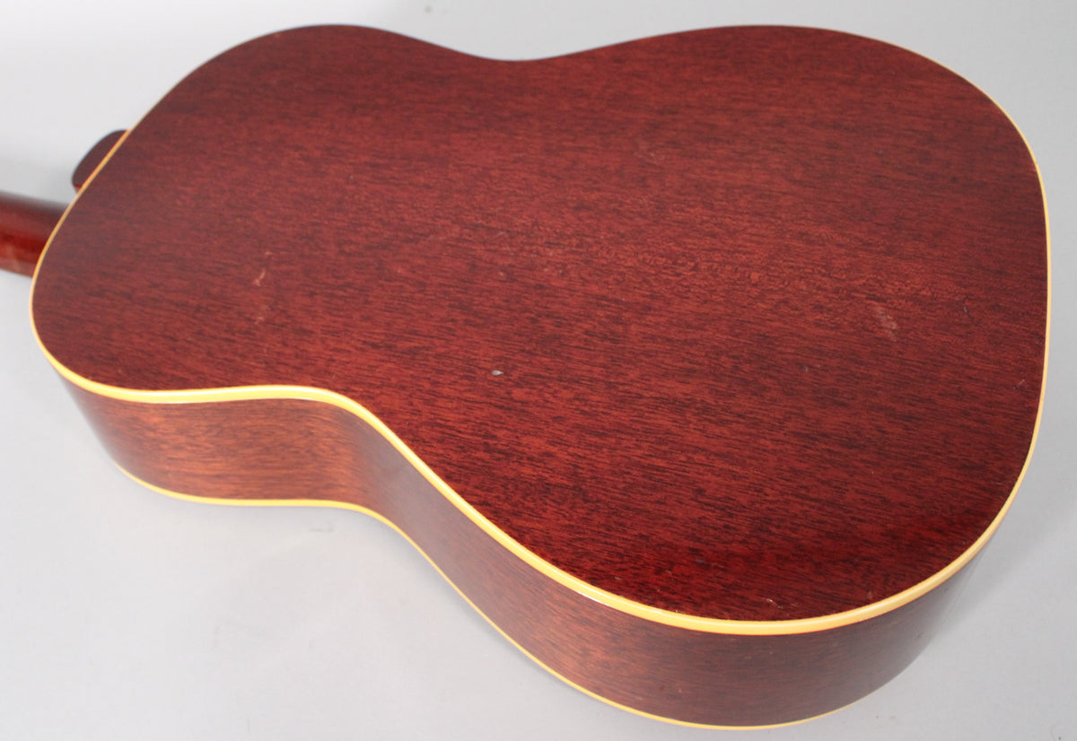 The back of the guitar, angled from the neck, shows a reddish-brown wood grain with light binding and some minor surface wear.