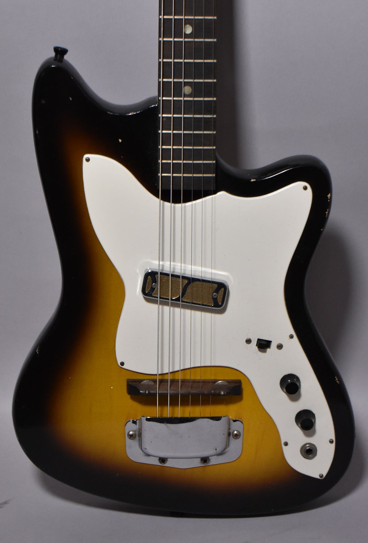Full-frame view of a sunburst electric guitar with a white pickguard, single gold foil pickup, and chrome tailpiece.