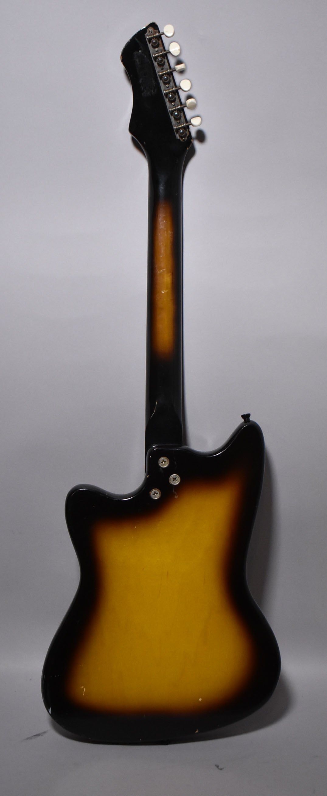 Back of a sunburst electric guitar, showing the body, neck, and headstock with six white-button tuners.