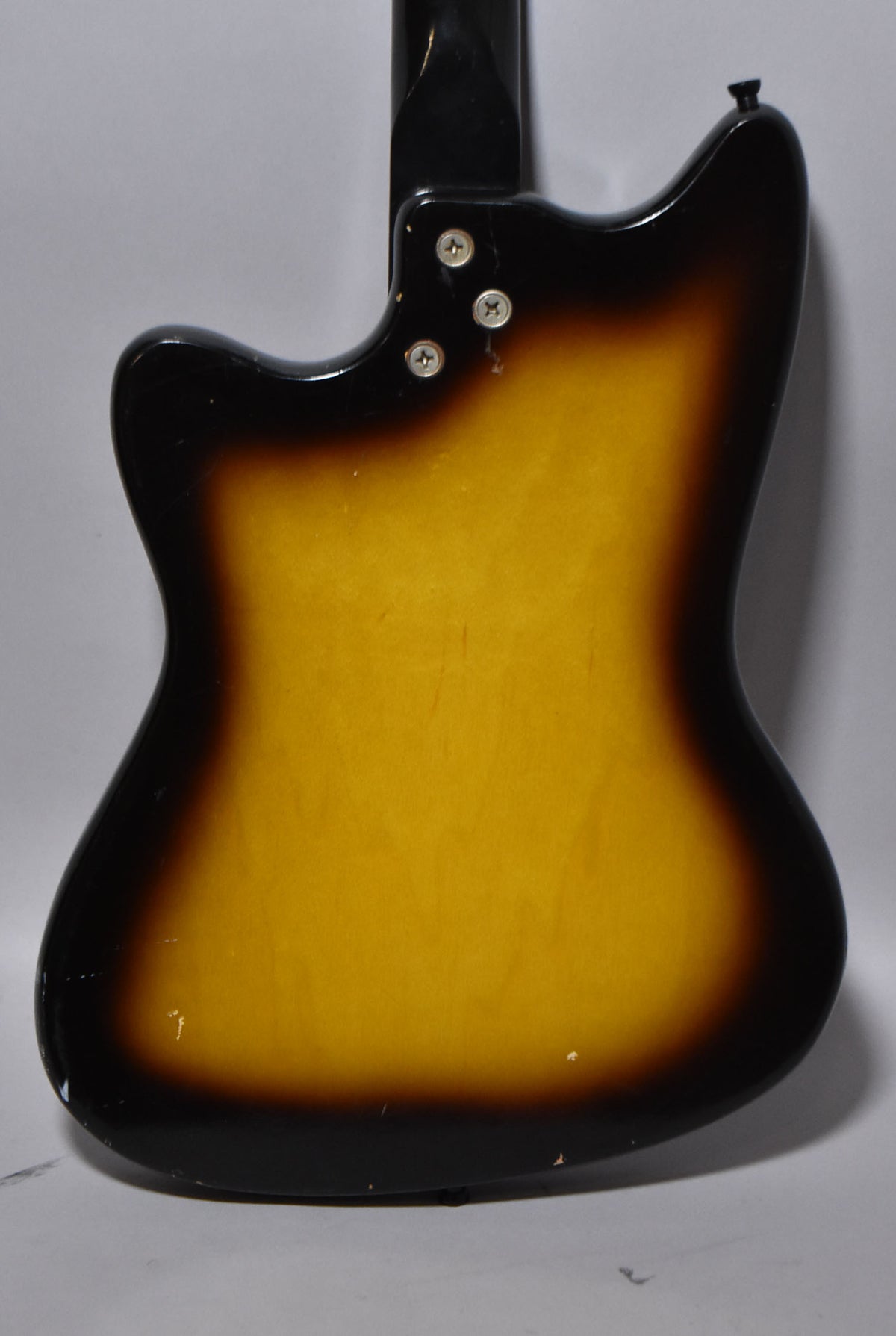 The guitar's back, showing a sunburst finish with a black neck joint and three neck plate screws, plus minor wear.