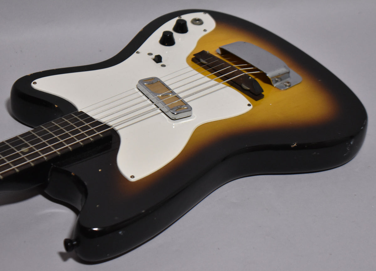 The sunburst electric guitar body, angled from the neck, shows a white pickguard, two black knobs, a single chrome pickup, and a bridge cover.
