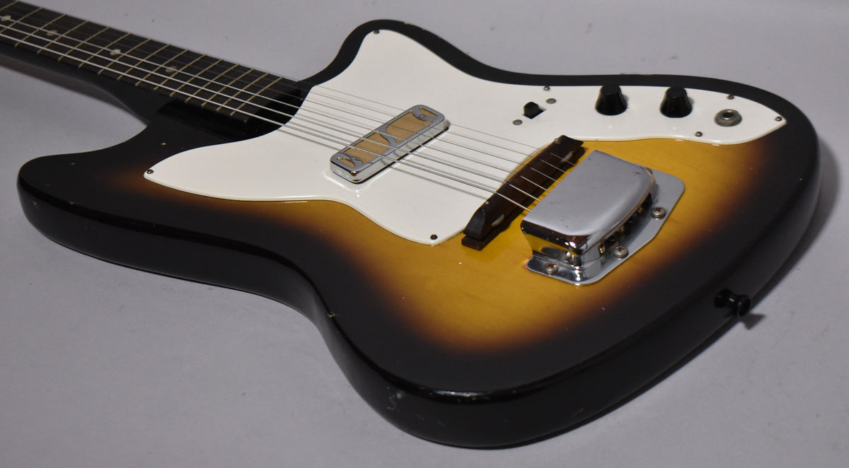 The guitar's body, with a worn sunburst finish and white pickguard, shows a chrome pickup and bridge cover.
