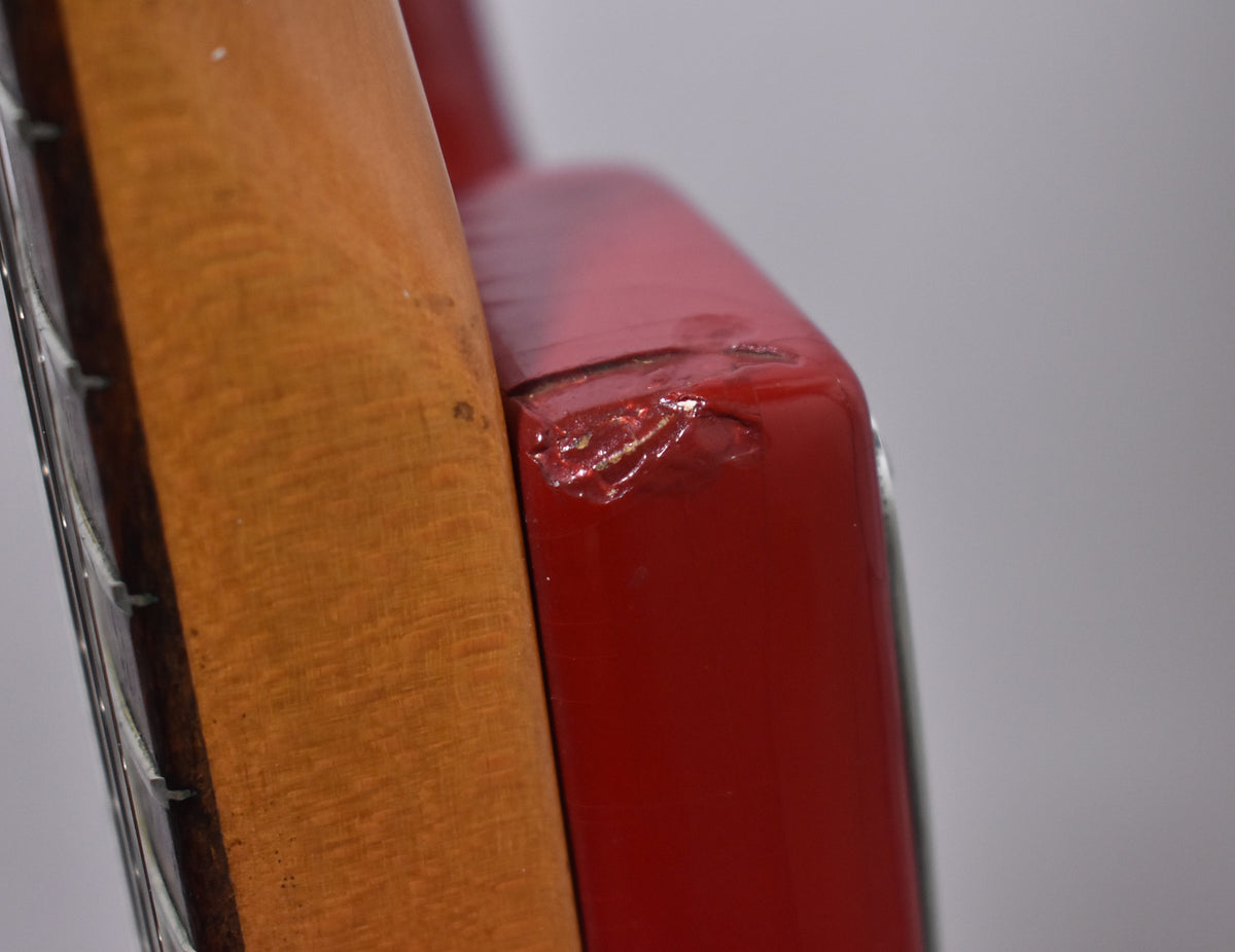 Close-up of the guitar's neck heel and body, showing significant paint chips and wear on the glossy Dakota Red finish.