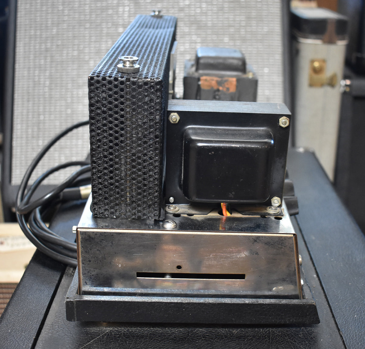 Close-up of the amp's rear, showing the black mesh tube cage, black transformers, and tarnished chrome chassis with a slot.