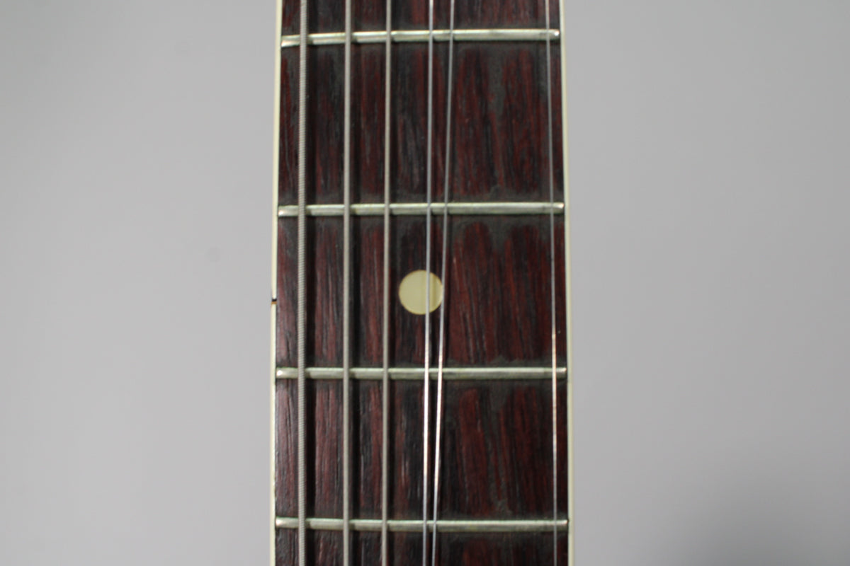 Close-up of the dark rosewood fretboard with a single cream dot inlay at the 7th fret, showing light wear on the frets.
