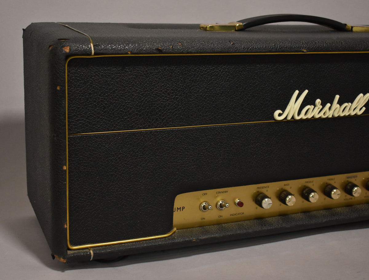 Black textured amplifier head, angled view of the front and left side, with a gold control panel and white knobs.