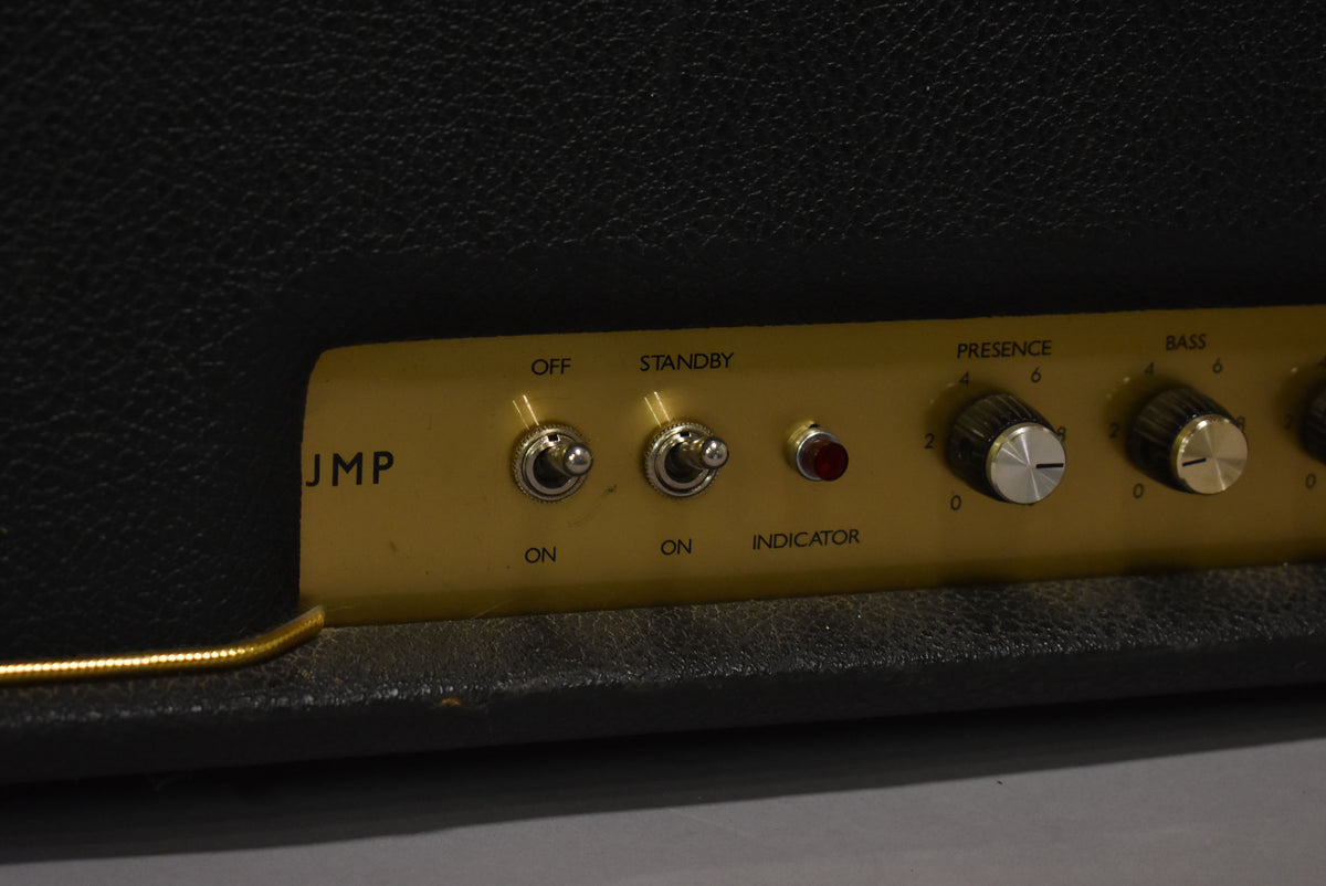 Close-up of the amp's gold control panel, showing two chrome toggle switches, a red indicator light, and two black-and-silver knobs.