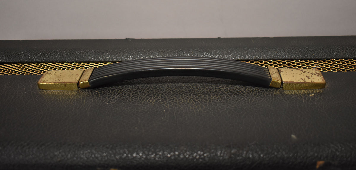 Top-down view of the black amp head, showing the ribbed black handle with tarnished gold-colored end caps and a gold mesh strip.