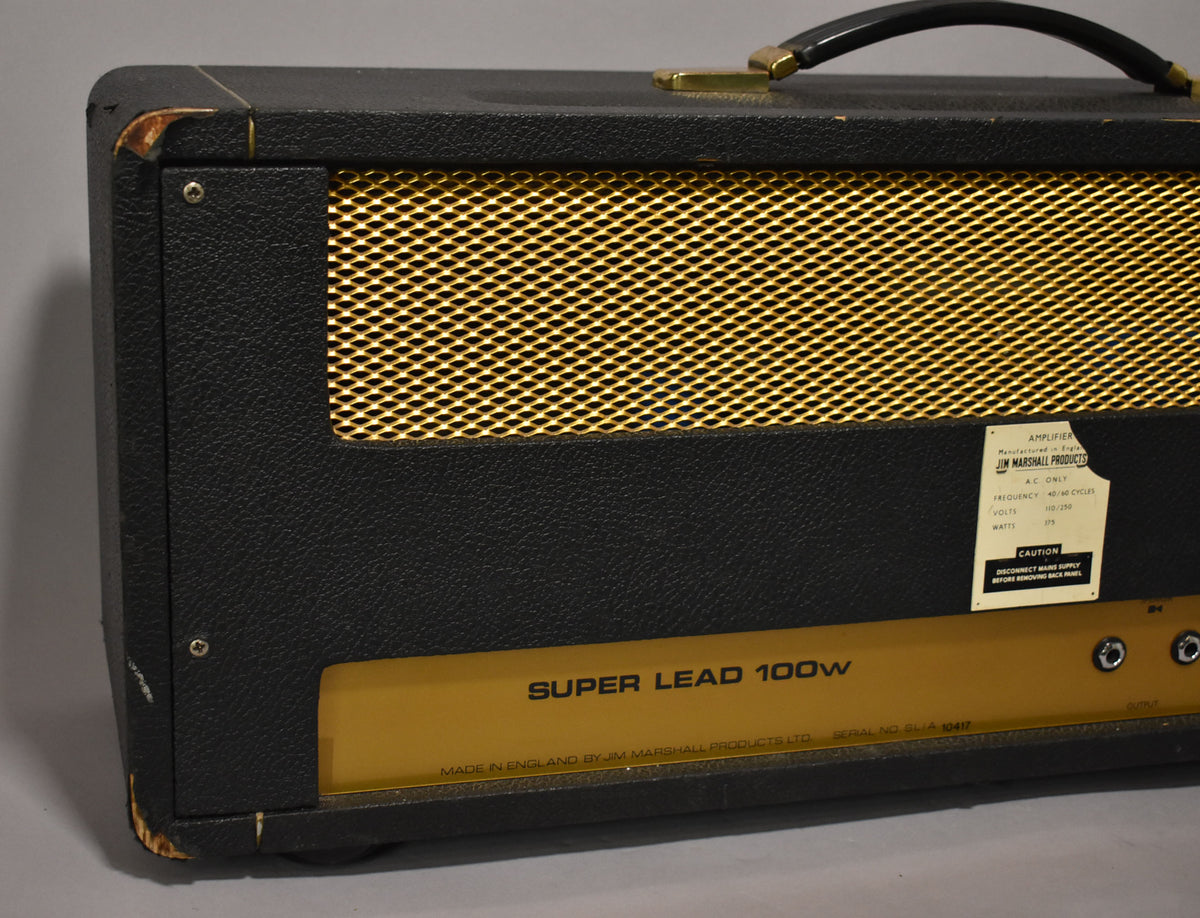 Close-up of a black Marshall Super Lead 100W amplifier head with a gold grille and label, showing wear on the corners.