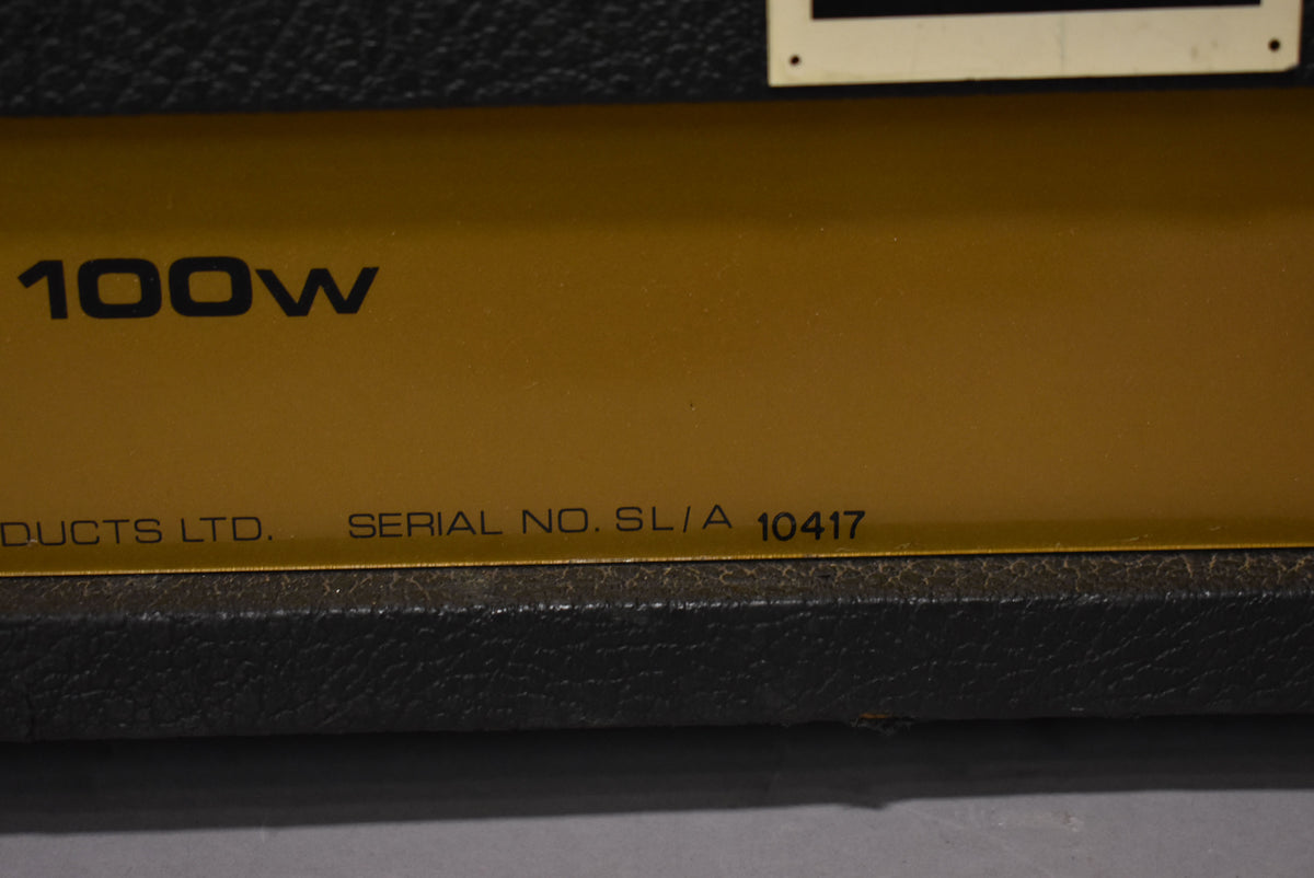 Close-up of the amp's gold-colored lower front panel, showing "100W" and "SERIAL NO. SL/A 10417" in black text.