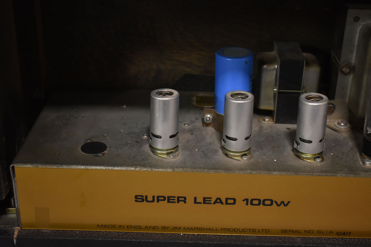Close-up of the amp's gold chassis with three silver tube covers, a blue capacitor, and a vacant tube socket, showing light wear.
