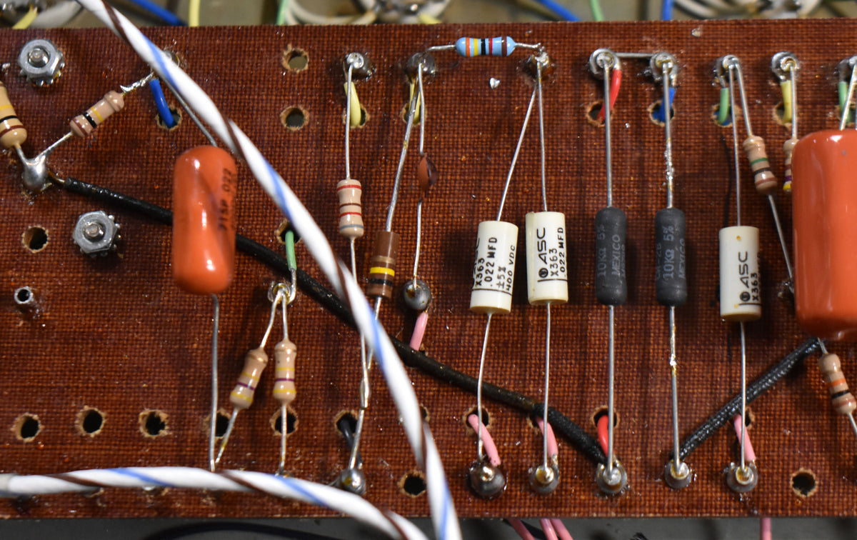 A close-up of the amplifier's brown circuit board shows various resistors and capacitors, with some visible wiring and solder joints.