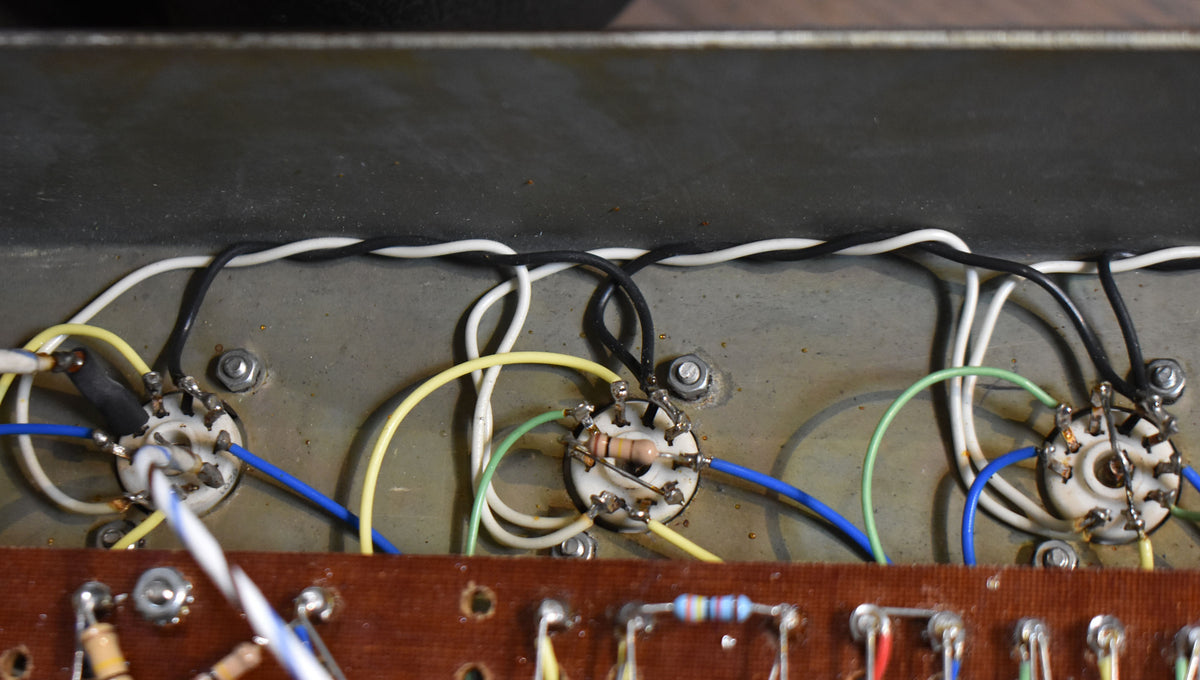 Close-up of the amp's internal wiring, showing three tube sockets with colorful wires, resistors, and a brown circuit board.