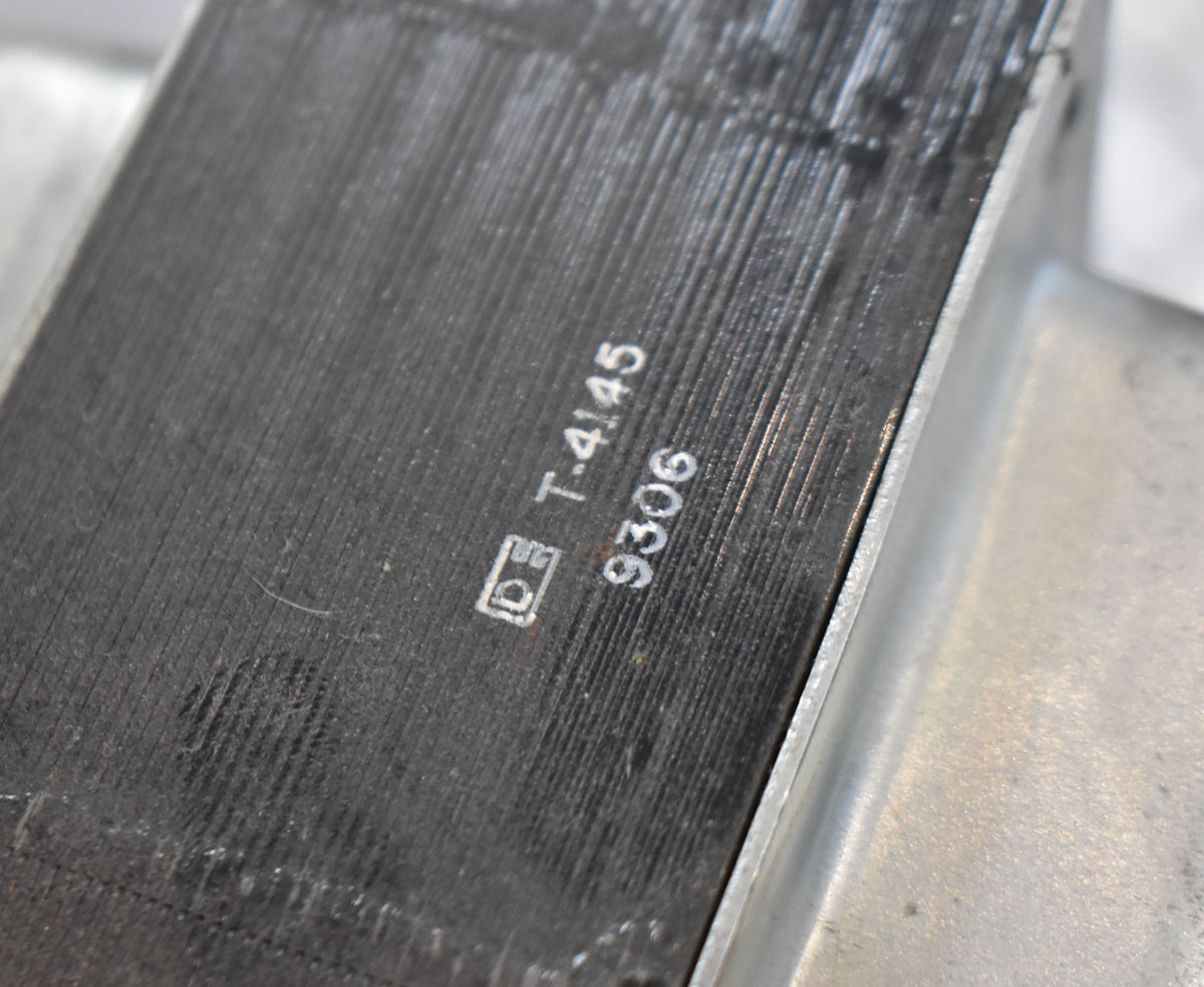 Close-up of a dark gray transformer with vertical striations, showing white stamped numbers "T-4145" and "9306".