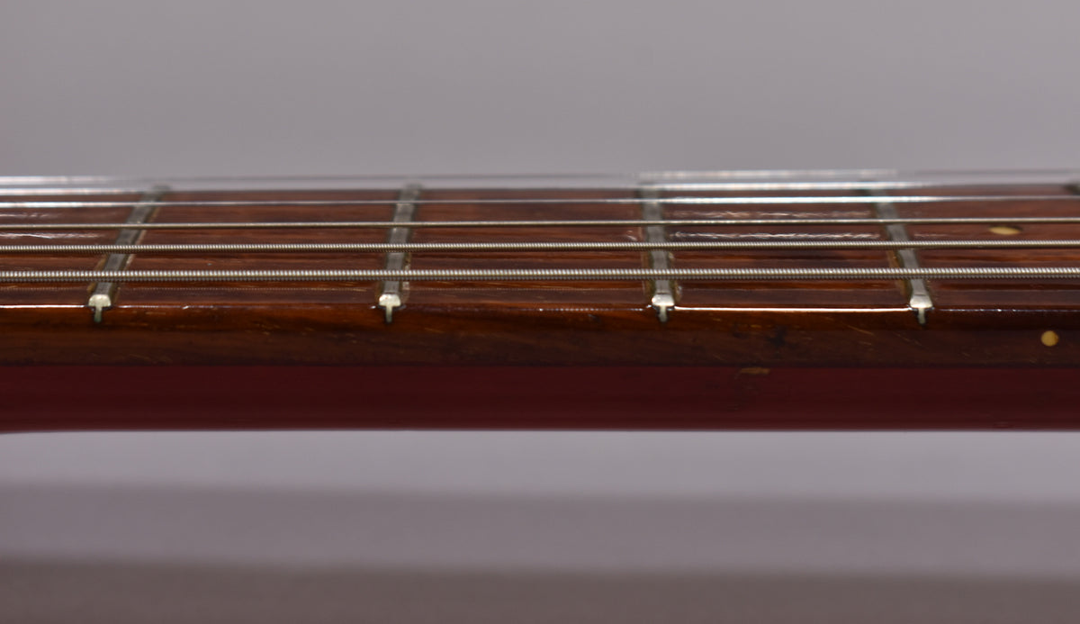 Close-up of the dark rosewood fretboard with light fret markers, showing minor wear and light string grooves.