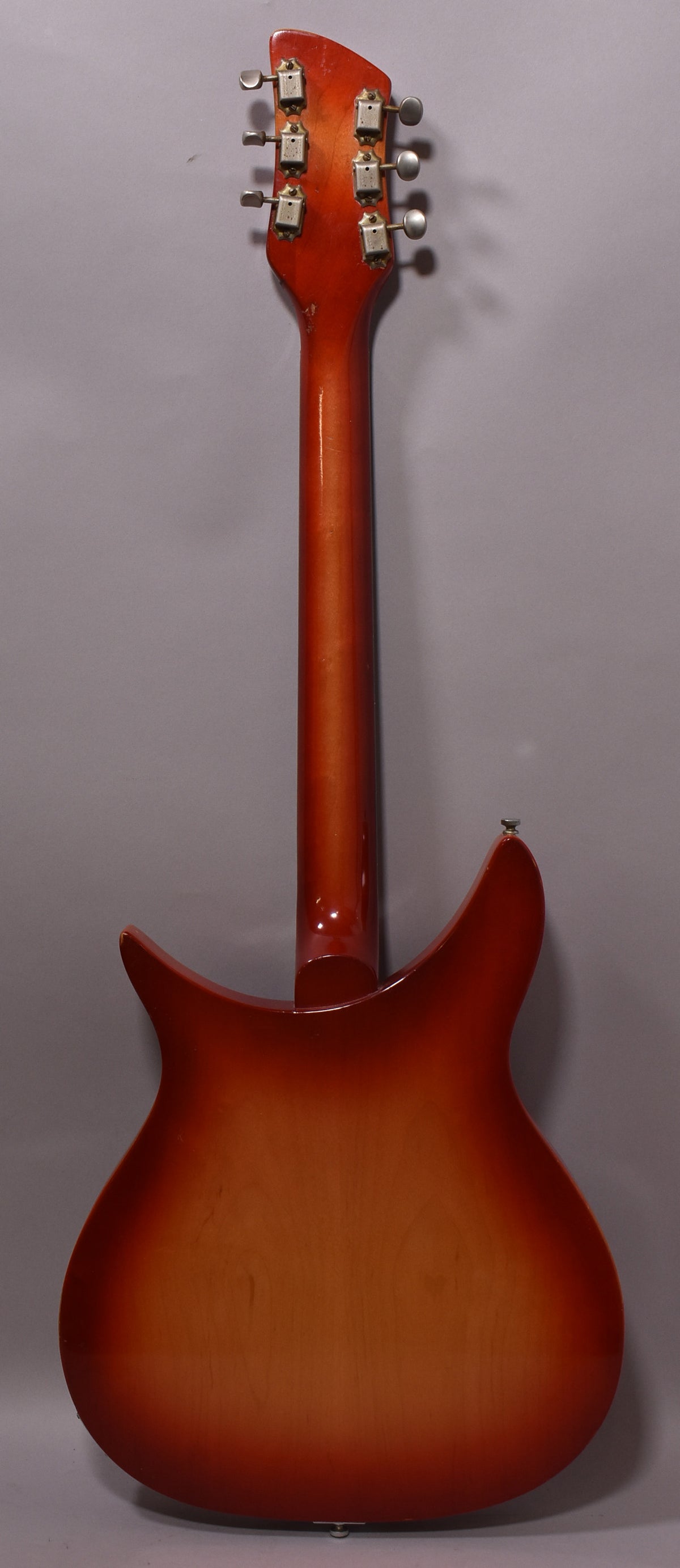 The back of a Fireglo guitar with a sunburst finish, showing the headstock with six tarnished tuners and a strap button.