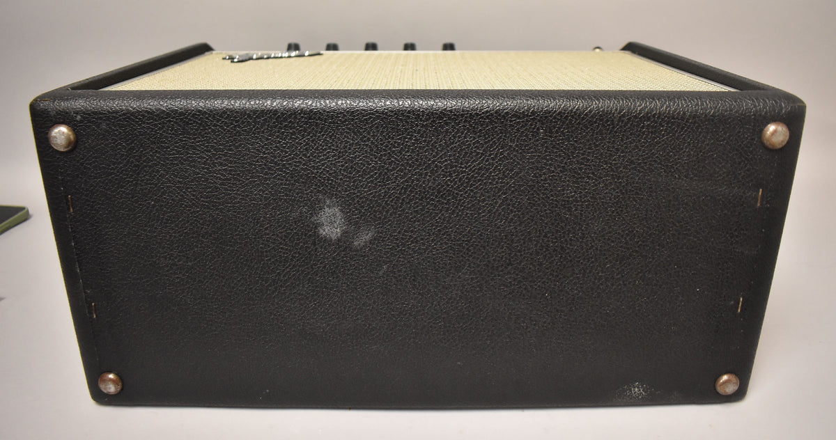 The amp's black textured vinyl top and sides are visible, with four silver corner protectors and a faded white scuff mark on the top.