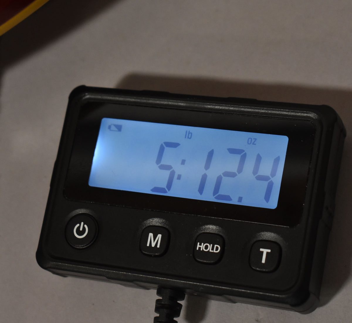 Close-up of a black digital scale displaying "5:12.4" in blue, indicating the guitar's weight in pounds and ounces.