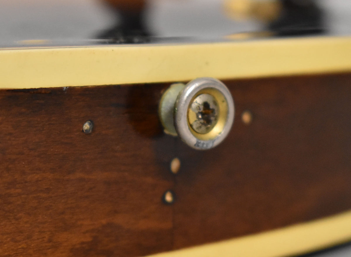 Close-up of the guitar's dark brown body binding and a worn chrome strap button with a gold center and visible screw.