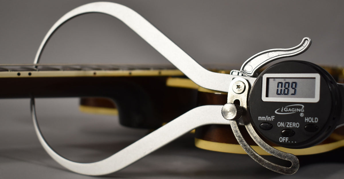 A digital caliper measures the guitar's action at the 12th fret, displaying 0.89mm, with the dark sunburst body visible.