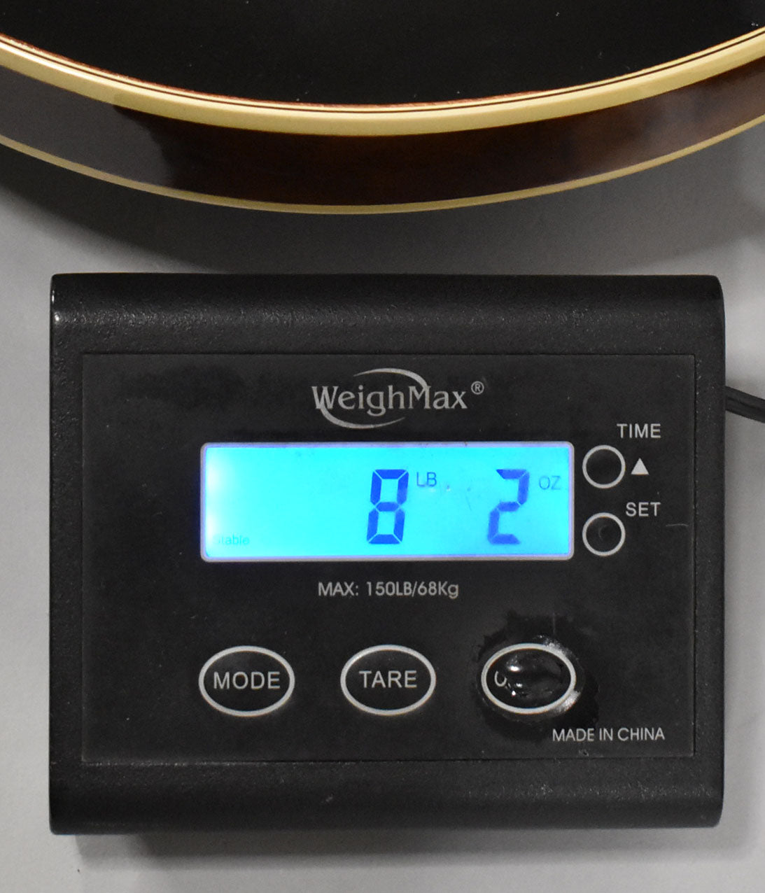 A close-up of a black digital scale showing "8 LB 2 OZ" with the guitar's dark sunburst body and binding visible at the top.
