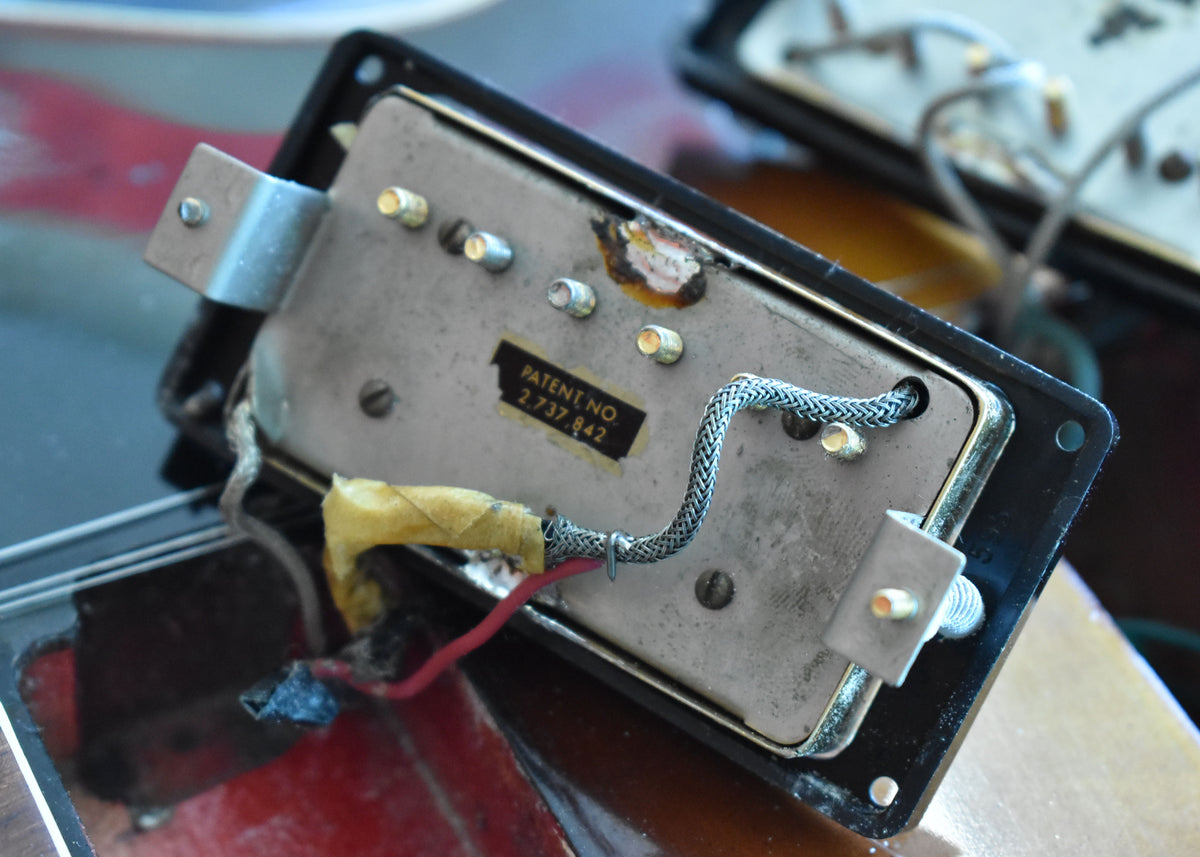 Close-up of the pickup's underside, showing the silver baseplate, braided wire, and a "PATENT NO." sticker with wear.