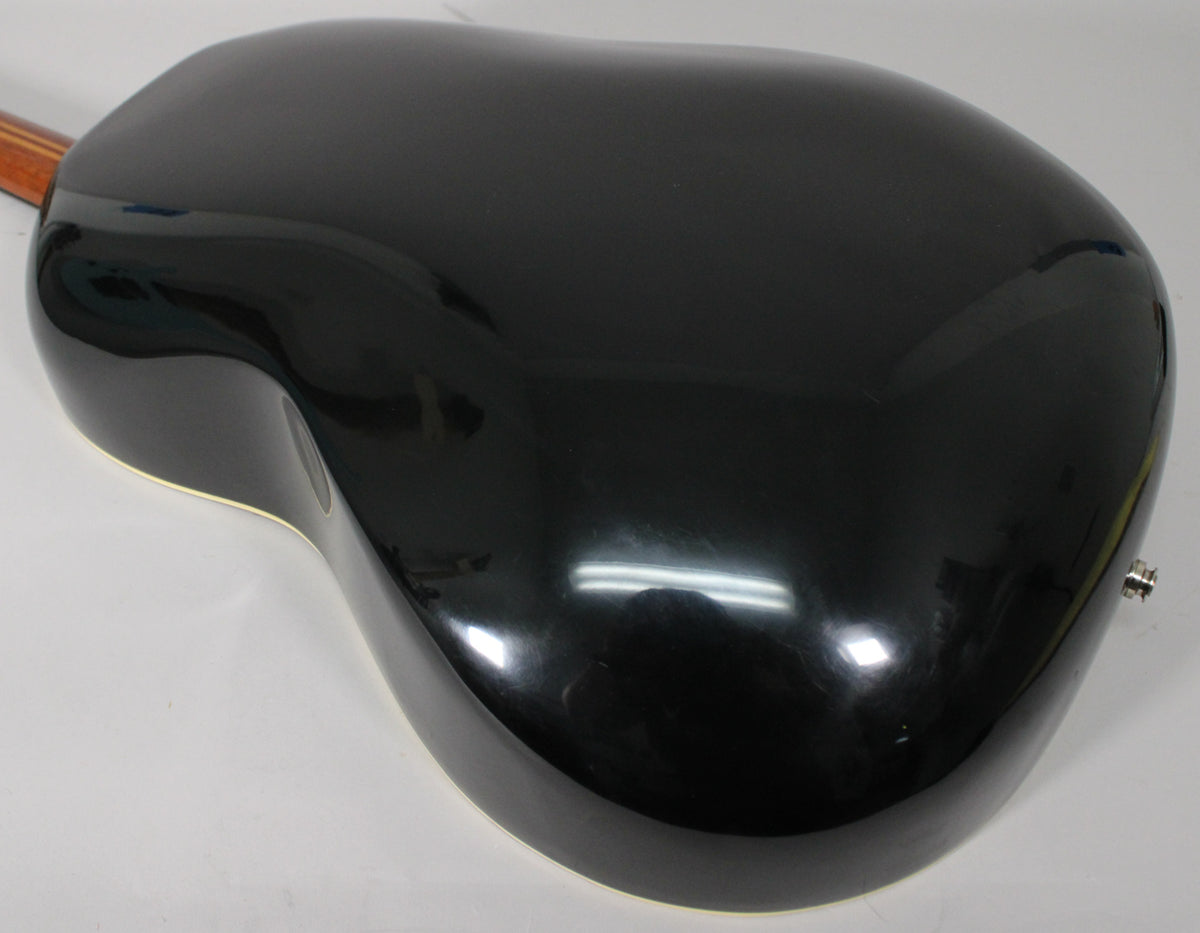 The guitar's glossy black bowl-back body is angled, showing a chrome endpin jack and a hint of the neck's wood grain.