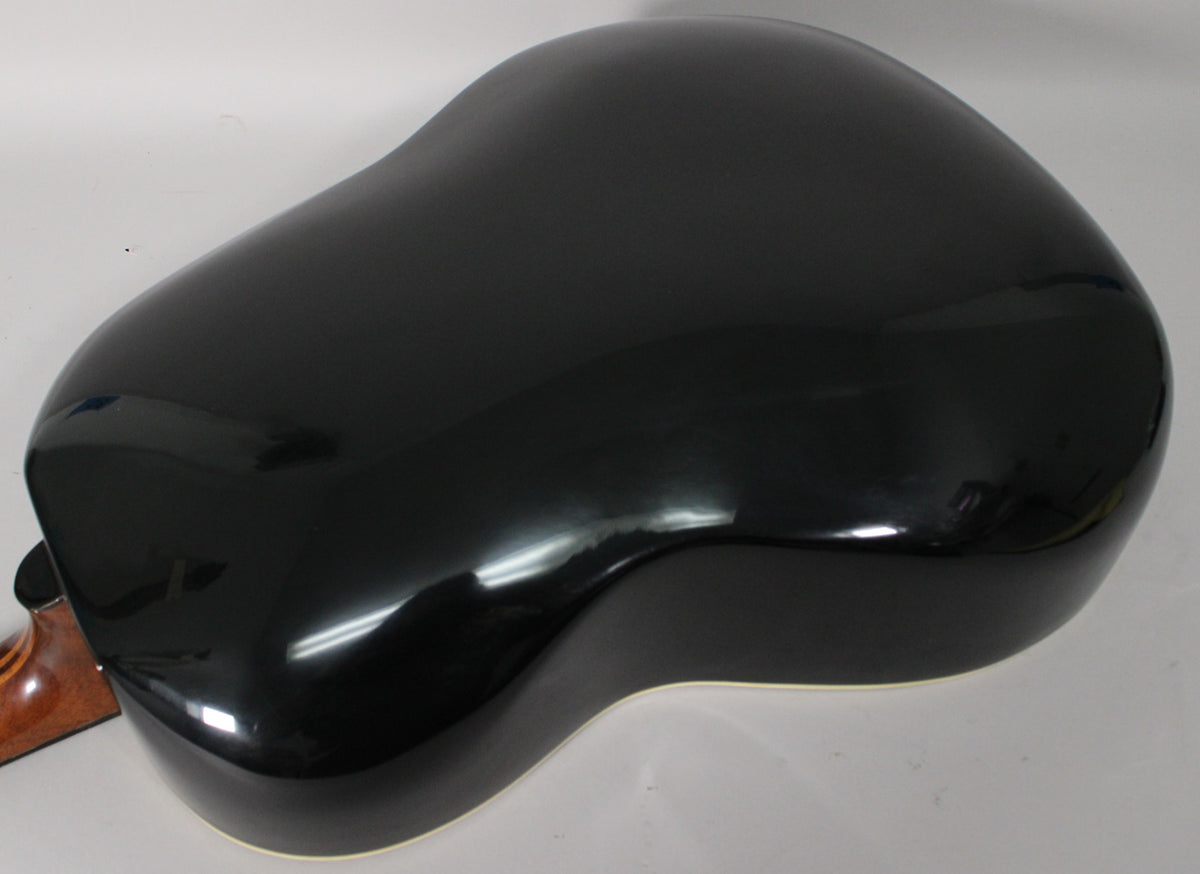 The guitar's shiny black bowl back is angled from the upper left, showing a few light scuffs and reflections, with a brown neck visible.