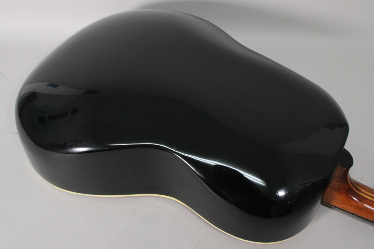The guitar's shiny black bowl-back body is angled, revealing a cream binding and a glimpse of the neck's wood grain.