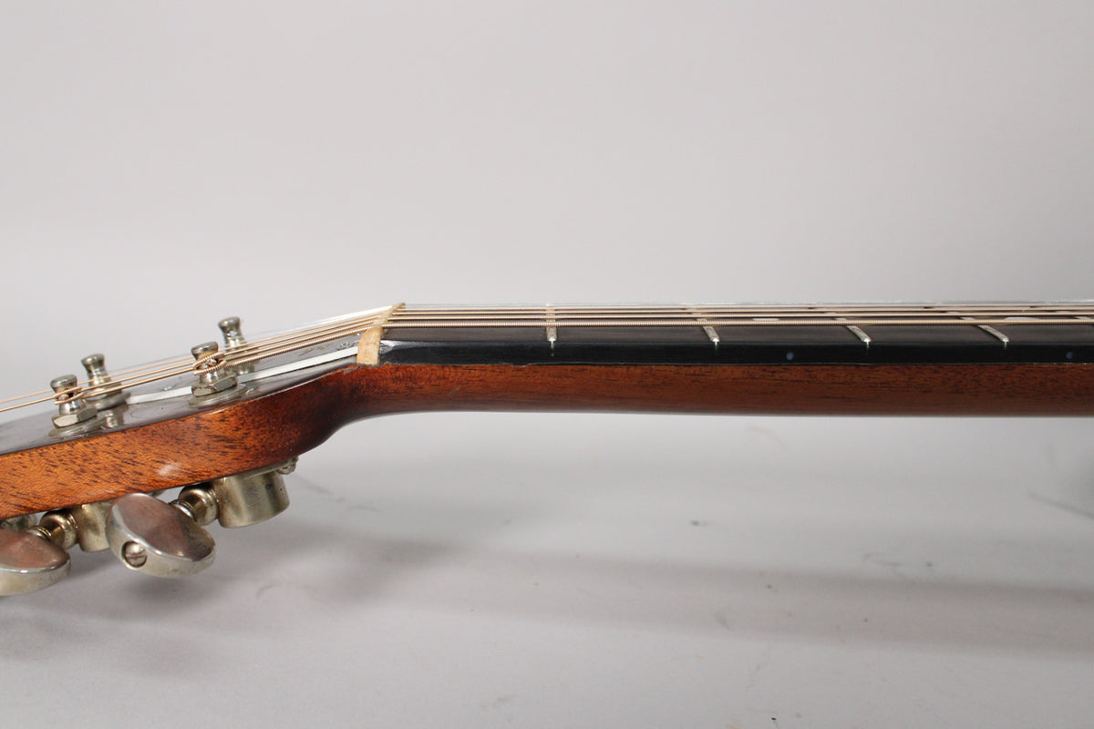 The guitar's headstock and upper neck are seen from the side, showing six metal tuners and a dark fretboard with light frets.